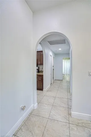Hallway with baseboards, arched walkways, and visible vents