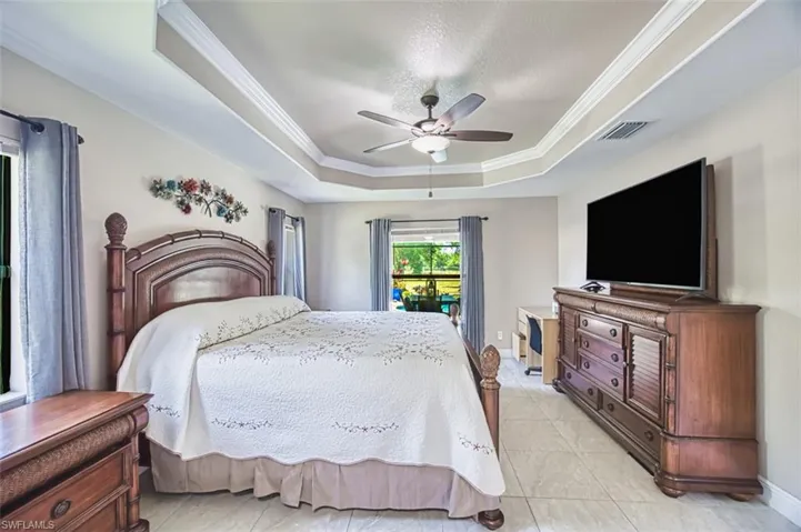 Bedroom with crown molding, light tile patterned flooring, visible vents, and a raised ceiling