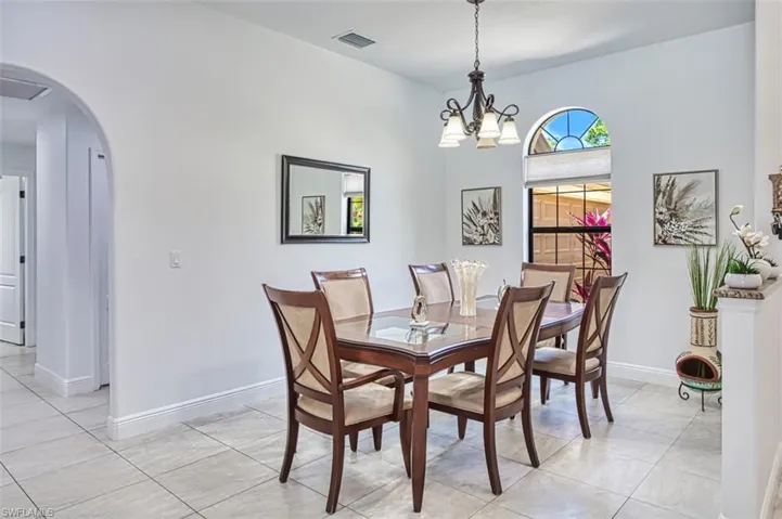 Dining space with arched walkways, baseboards, a notable chandelier, and visible vents