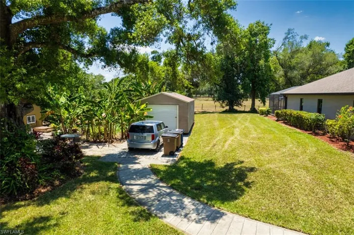 View of yard with a garage, a storage unit, and an outbuilding