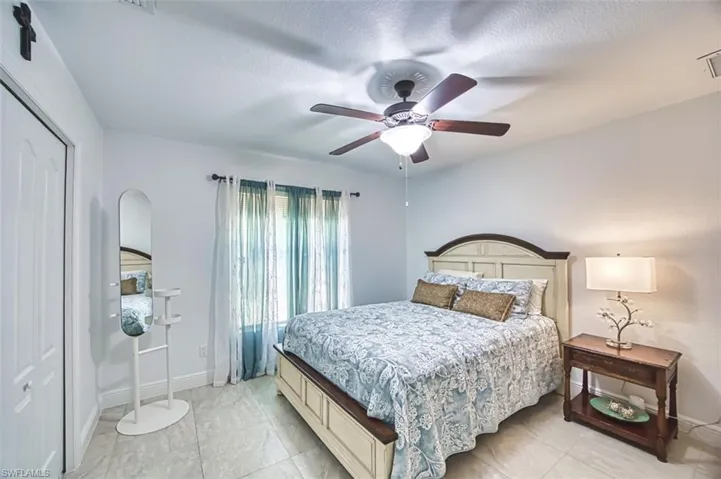 Bedroom with baseboards, arched walkways, a textured ceiling, and ceiling fan