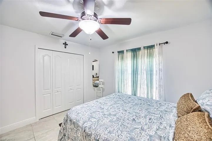 Bedroom featuring visible vents, a closet, baseboards, ceiling fan, and light tile patterned floors