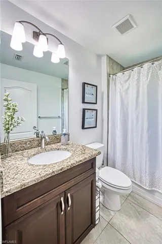 Bathroom featuring toilet, visible vents, marble finish floor, and vanity