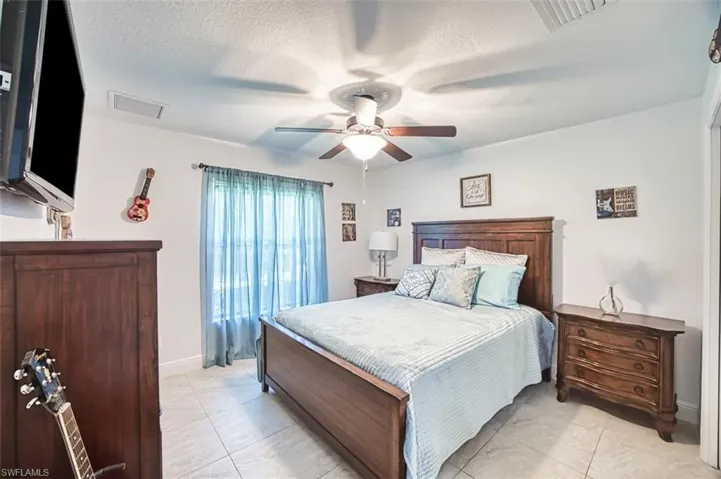 Bedroom with visible vents, a textured ceiling, baseboards, and ceiling fan