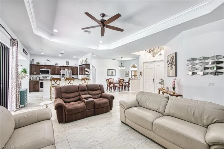 Living area featuring visible vents, ornamental molding, recessed lighting, a raised ceiling, and ceiling fan with notable chandelier