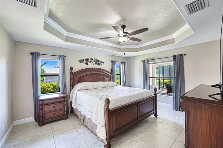 Bedroom featuring visible vents, ornamental molding, and a raised ceiling