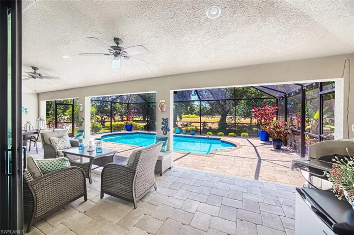 Outdoor pool featuring a lanai, a patio, a ceiling fan, and a grill