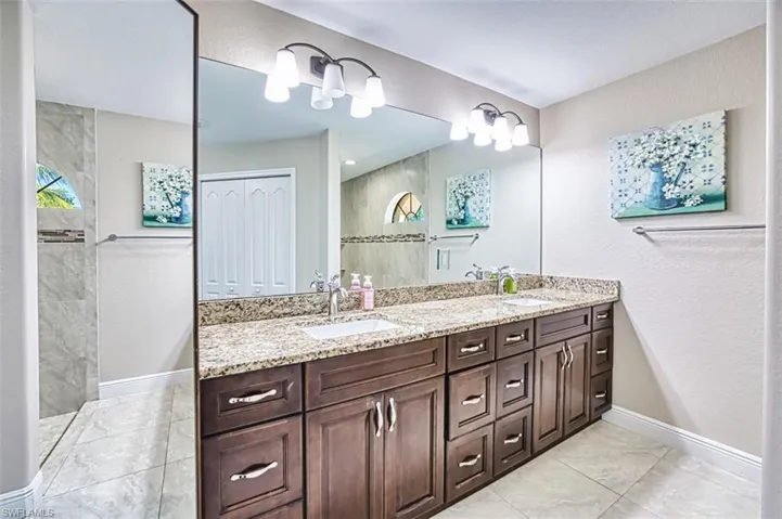 Bathroom featuring a sink, a walk in shower, double vanity, and marble finish floor