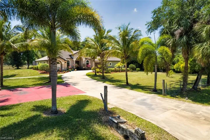 View of community with concrete driveway and a yard
