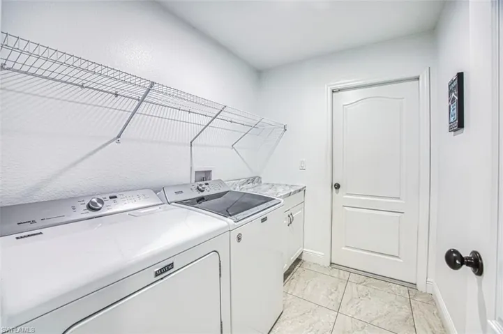 Clothes washing area with baseboards, marble finish floor, cabinet space, and independent washer and dryer