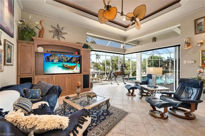 Tiled living room featuring a tray ceiling, zero corner double sliders to lanai/pool