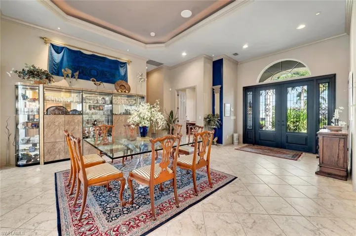 Dining room with tray ceiling, crown molding, diagonal tile floors. Front entry with glass double doors.