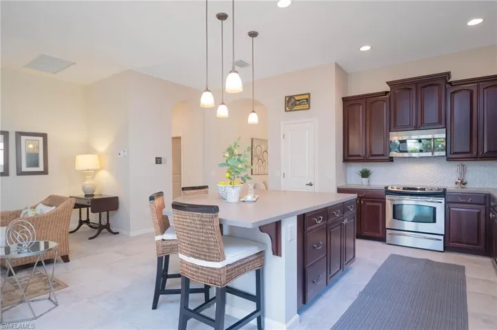 Kitchen featuring a center island, stainless steel appliances, decorative light fixtures, a breakfast bar, and dark brown cabinets
