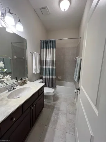 Full bathroom with shower / bath combination with curtain, tile patterned floors, vanity, a textured ceiling, and toilet
