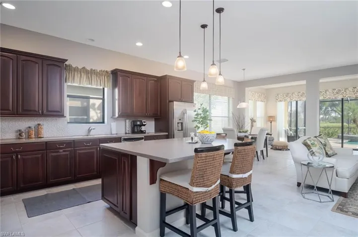 Kitchen with a kitchen bar, a kitchen island, hanging light fixtures, and stainless steel refrigerator with ice dispenser