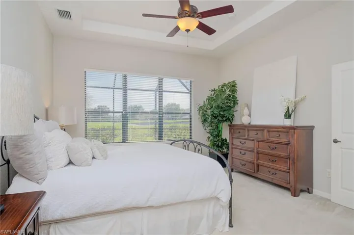 Bedroom featuring ceiling fan, a raised ceiling, and light colored carpet