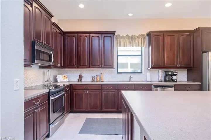 Kitchen with light tile patterned floors, sink, appliances with stainless steel finishes, and tasteful backsplash