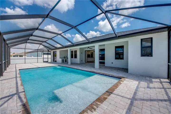 Swimming pool featuring a sunroom, a ceiling fan, a patio area, and glass enclosure