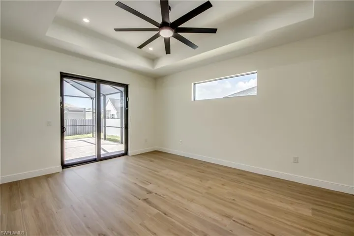 Spare room with a raised ceiling, light wood-type flooring, recessed lighting, and ceiling fan