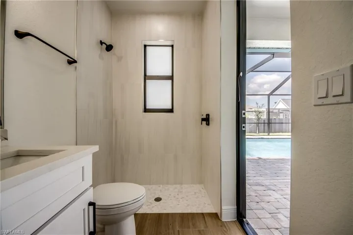 Bathroom with a textured wall, a stall shower, healthy amount of natural light, vanity, and wood finished floors