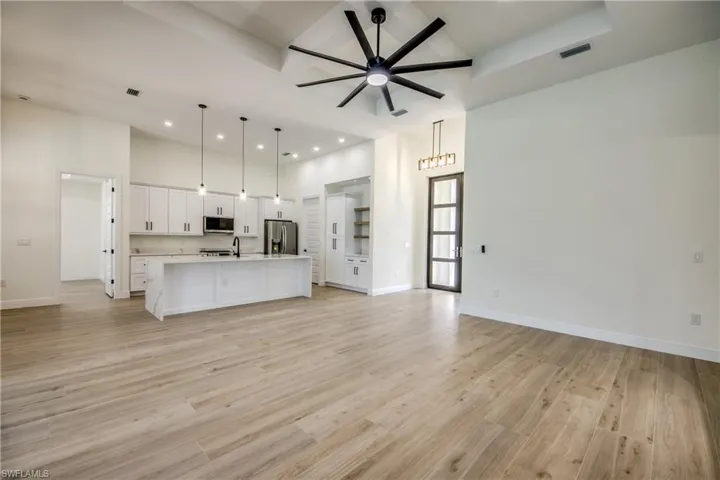 Unfurnished living room with a ceiling fan, recessed lighting, light wood-type flooring, and a high ceiling