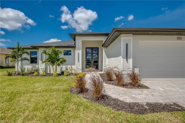 View of front of house featuring stucco siding, a front yard, decorative driveway, and a garage