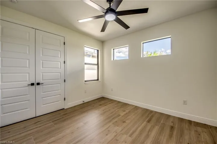 Unfurnished bedroom featuring multiple windows, light wood-type flooring, a closet, and ceiling fan