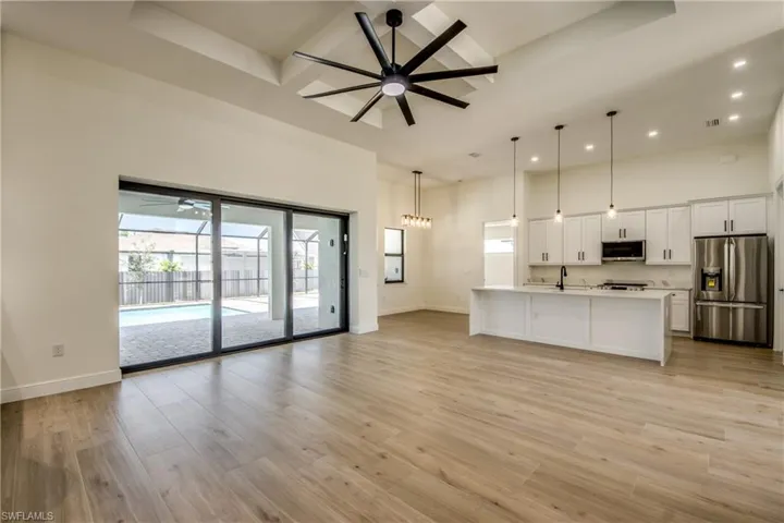 Unfurnished living room featuring a ceiling fan, light wood-style floors, recessed lighting, and a high ceiling