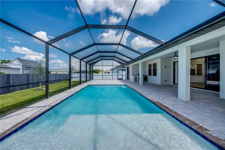 View of pool featuring a sunroom, glass enclosure, a patio, and a ceiling fan