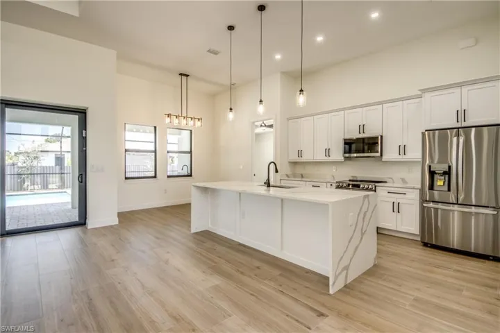 Kitchen featuring appliances with stainless steel finishes, light stone counters, a center island with sink, pendant lighting, and recessed lighting