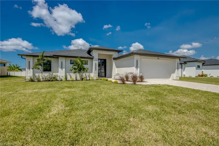 Prairie-style house with a front yard, decorative driveway, a garage, and stucco siding