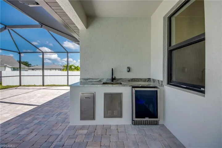 View of patio / terrace featuring a sunroom, area for grilling, glass enclosure, and beverage cooler