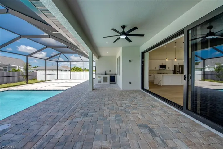View of patio with an outdoor kitchen, a sunroom, a lanai, and beverage cooler
