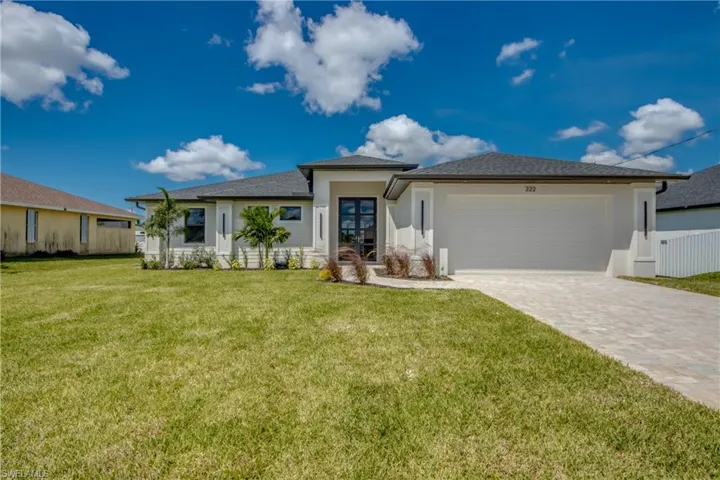 Prairie-style house featuring a front lawn, decorative driveway, stucco siding, and a garage