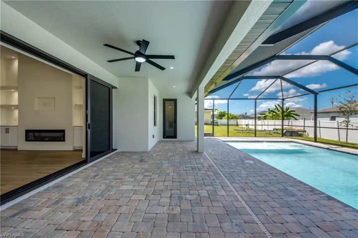 View of swimming pool with a patio, a sunroom, ceiling fan, and glass enclosure