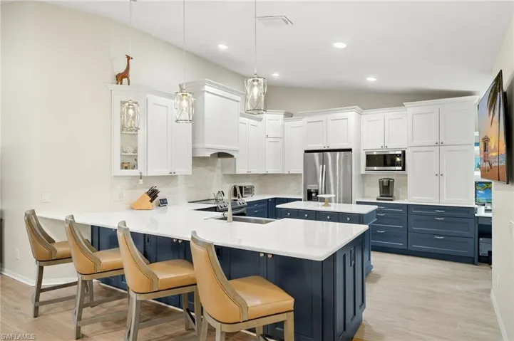 Kitchen with white and navy cabinetry, stainless steel appliances and a peninsula