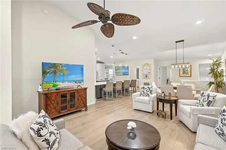 Living area with recessed lighting, ceiling fan, light wood floors and vaulted ceiling