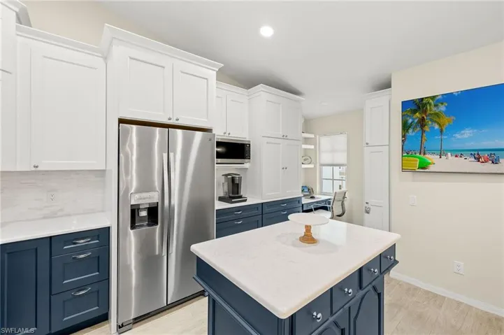 Kitchen featuring decorative backsplash, blue cabinetry, white cabinets, and stainless steel appliances