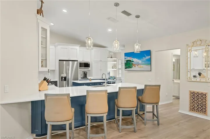 Elegant kitchen featuring quartz countertops,  white upper and navy lower shaker cabinetry, pendant and recessed lighting.