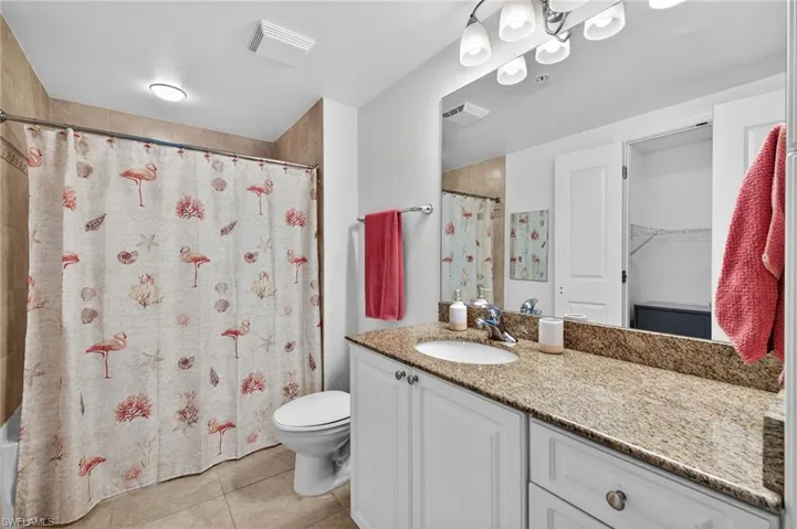 Full bathroom with vanity, light tile patterned flooring, a spacious closet, and shower / bathtub combination with curtain
