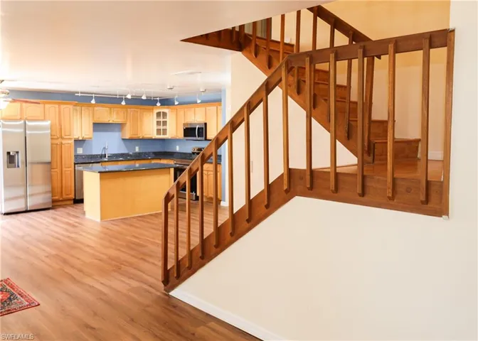 Stairs featuring rail lighting and wood finished floors
