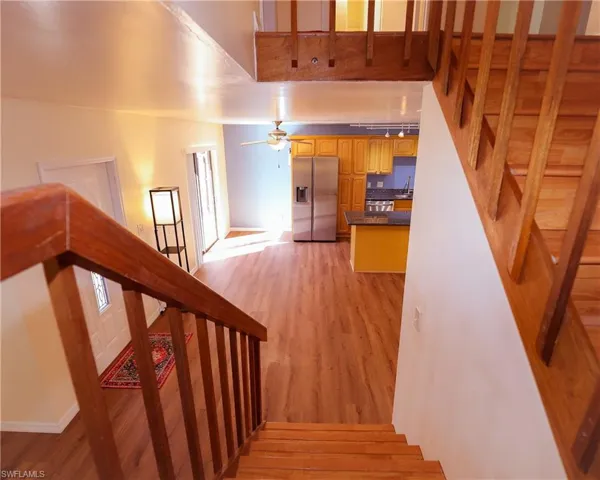 Stairs with wood finished floors and a ceiling fan