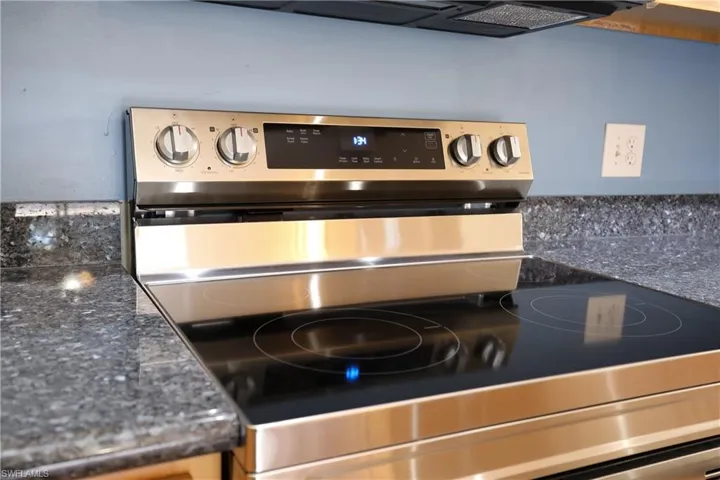 Kitchen view of electric range and dark stone counters