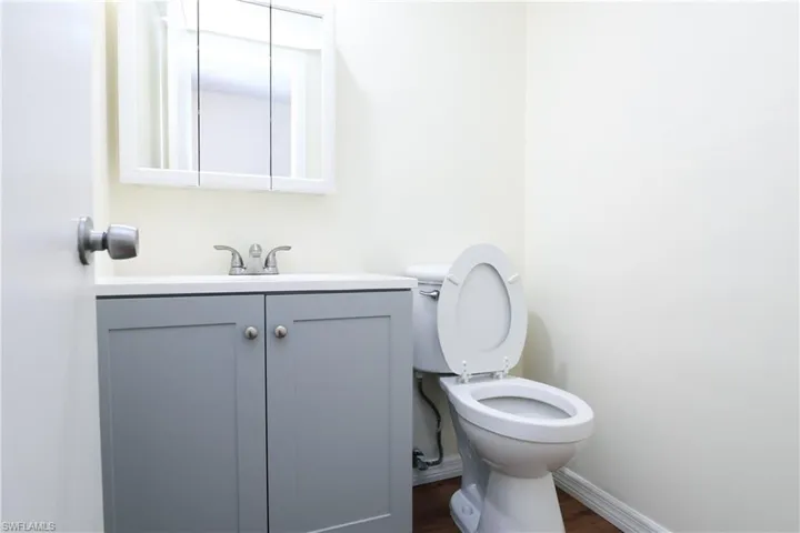 Half bathroom featuring vanity and dark wood-type flooring