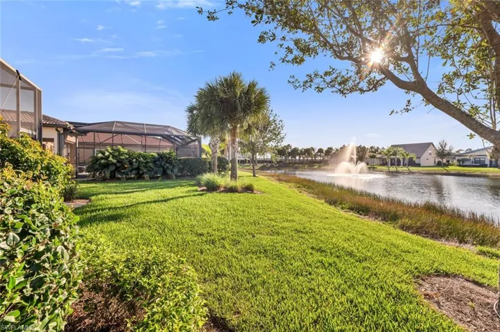 View of green lawn featuring a sunroom, a water view, and a lanai