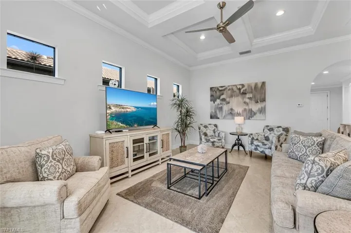 Living area featuring arched walkways, a ceiling fan, coffered ceiling, crown molding, and recessed lighting