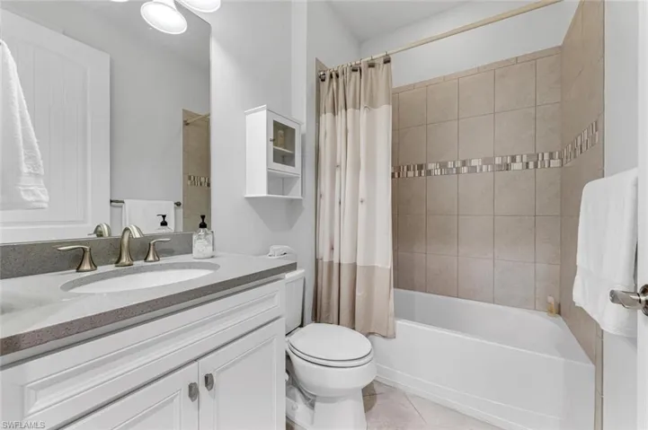 Full bath with vanity, shower / bath combo, and light tile patterned floors