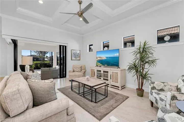 Living area featuring coffered ceiling, beam ceiling, a ceiling fan, and ornamental molding