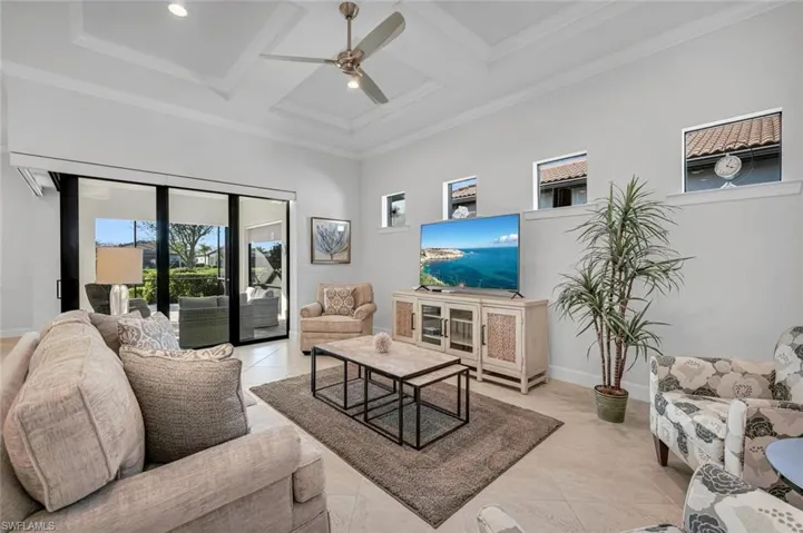 Living area with coffered ceiling, beam ceiling, light tile patterned flooring, a ceiling fan, and a high ceiling
