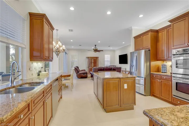 Kitchen featuring decorative backsplash, open floor plan, appliances with stainless steel finishes, brown cabinets, and crown molding